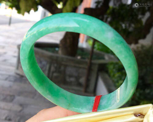 A NATURAL JADEITE OVAL SHAPED BANGLE