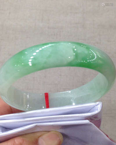 A NATURAL JADEITE OVAL SHAPED BANGLE