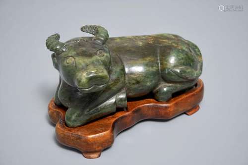 A CHINESE SPINACH GREEN JADE MODEL OF AN OX ON WOODEN STAND, 19/20TH C.