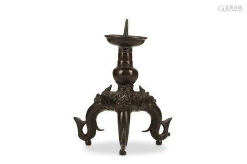 A BRONZE CANDLE STICK. 17th to 18th Century. Supported on tripod S-shaped feet with bifurcated