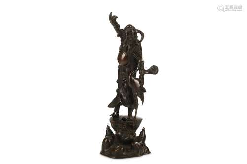 A CHINESE BRONZE MODEL OF AN IMMORTAL. Late Ming to early Qing Dynasty. Standing on a rocky base