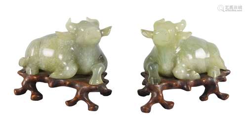 A pair of Chinese green hardstone buffalo, 20th century, each carved in recumbent pose, on fitted