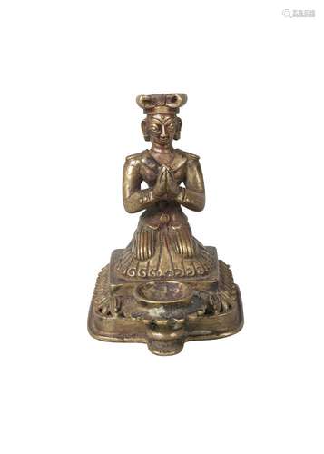 A Nepalese bronze figural lamp, 19th century, modelled with a kneeling man praying, behind oil