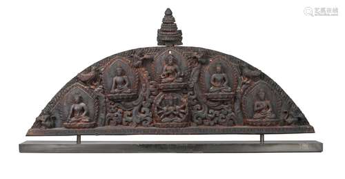 A Nepalese black wood lintel relief (torana), 19th century, of arched form, surmounted with a stupa,