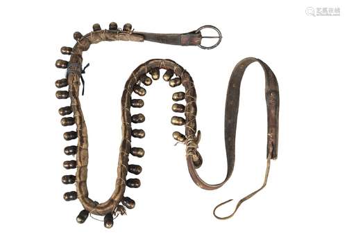 A Nepalese animal belt, late 19th century, adorned with brass bells, with yellow silk scarf, 110cm