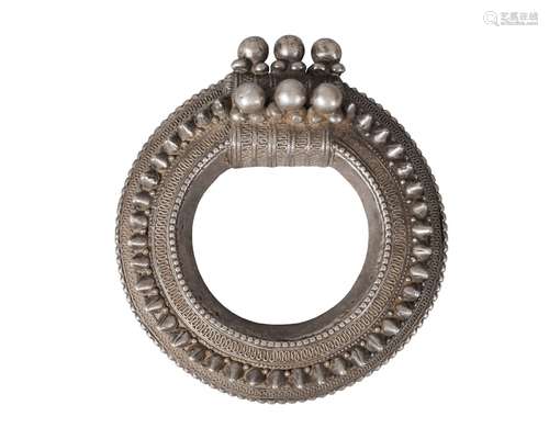 A Nepalese white metal bangle, 19th century, studded and with filigree decoration, 15cm diameter