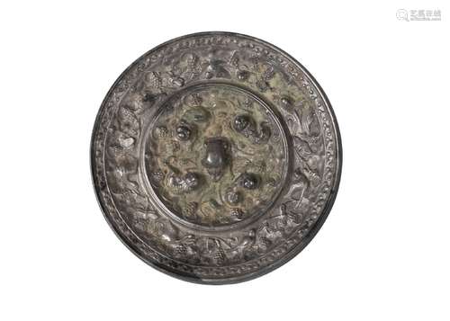 A Chinese silvered bronze 'Lion and Grape' mirror, Tang dynasty, with central crouching lion knop,