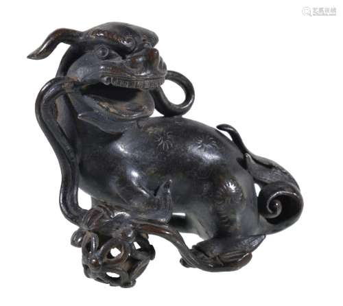 A small Chinese bronze Buddhist lion, Ming Dynasty, cast with the right forepaw resting on a