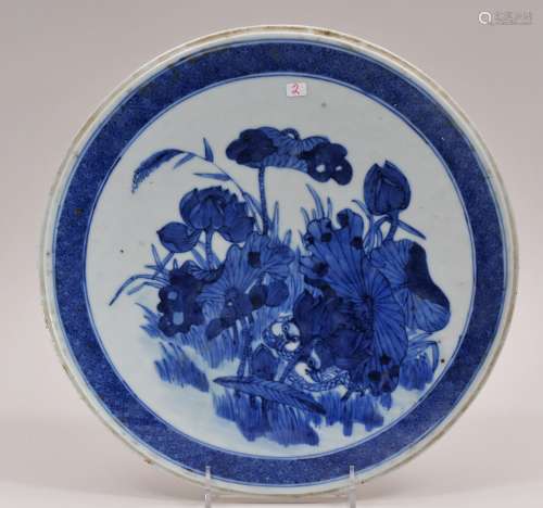 Round porcelain plaque. China. 19th century. Underglaze blue decoration of a pair of mandarin ducks swimming in a lotus pond. 12-1/4