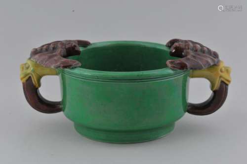 Porcelain two handled cup. China. 19th century. San Tsai ware. Green body with  bat and foo dog handles of aubergine and yellow. Small chips to underside of one bats wing. 6-1/2