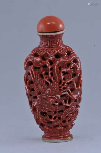 Snuff bottle. China. 19th century. Carved porcelain. Design of dragons and clouds. Cinnabar color. Coral stopper. 2-7/8