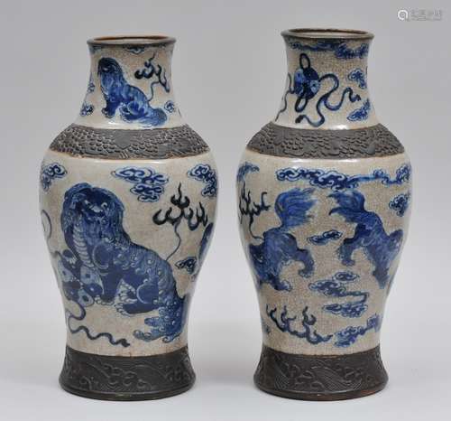 Pair of porcelain vases. China. Late 19th to early 20th century. Underglaze blue decoration of foo dogs, brocade balls and clouds on a crackled ground. Unglazed burnt brown borders of carved flowers and waves. 15