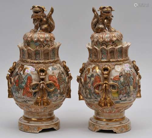 Pair of pottery covered jars. Japan. Meiji period. (1868-1912). Satsuma ware. Shaped bodies with bows. Decoration of scholars and buddhist saints. Inscription around the foot. 12-7/8