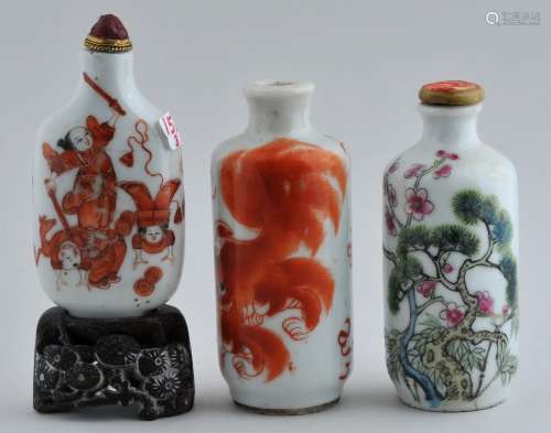 Lot of three snuff bottles. China. 19th century. To include: Two with iron red decoration of foo dogs and an historical scene. The other with The Three Friends, Pine, Prunus and Bamboo in Famille Rose enamels. Each about 3