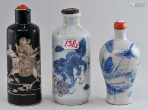 Lot of three snuff bottles. China. 19th century. To include: One with foo dogs in underglaze blue and red, an underglaze blue bottle decorated with insects and another bottle of white resist of black with Shu Ko. Each about 3-1/4