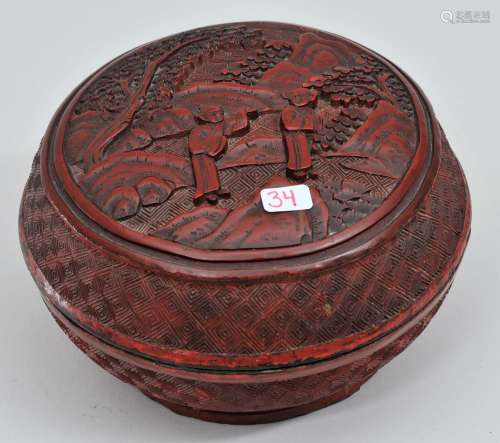 Cinnebar box. China. 19th century. Round form. Central reserve of figures in a garden. Borders carved with a diamond pattern. Repairs to edges. Loss to the foot rim. 5