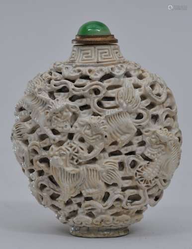 Snuff bottle. 19th century. White porcelain carved with foo dogs, brocade balls and clouds. 2-5/8