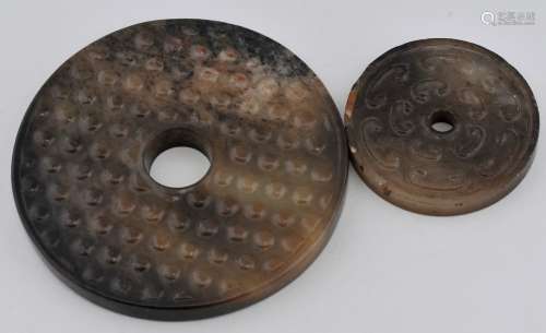 2 Jade Pi. China. 18th century or earlier. Brown jade with black markings. Surfaces with grain pattern. 3-3/4