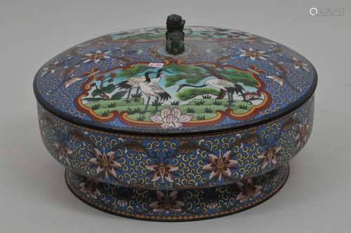 Cloisonné covered bowl. China. 20th century. Foo dog finial. Decoration of reserves of cranes on a stylized lotus scroll ground on blue. 10-1/2