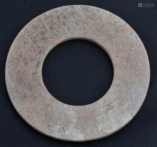 Ritual Jade. China. Han style. Pi of much calcified tan coloured stone. Surface carved with archaic scrolling. 3-1/2
