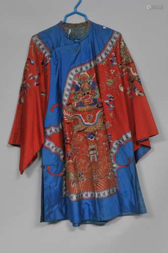 Silk robe. China. Early 20th century. Embroidery of dragons, phoenixes, foo dogs and pavillions on a red ground with blue borders.