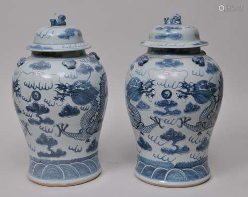 Pair of porcelain covered jars. China. 19th century. Decoration of dragons and clouds in underglaze blue. Foo dog finials and lugs.  SIZE