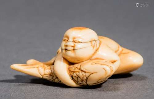 AN IVORY NETSUKE OF A BOY WITH A CARP