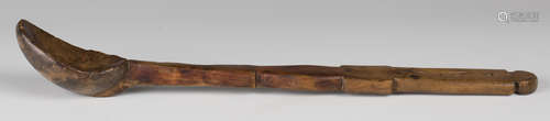 A 19th century Welsh yew wood long handled spoon with a shaped shaft and curved bowl