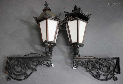 A pair of early 20th century Continental cast iron wall mounted street lanterns with foliate scrolling supports