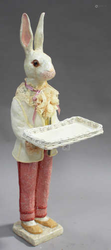 A late 20th century moulded composition figure of a standing rabbit holding a wicker tray