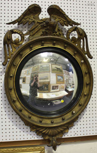A Regency giltwood and gesso circular convex wall mirror with phoenix surmount and ballshot border
