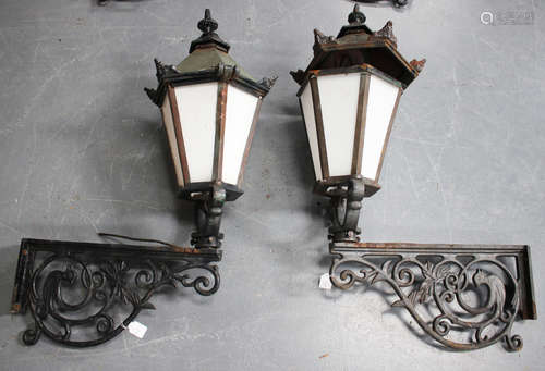 A pair of early 20th century Continental cast iron wall mounted street lanterns with foliate scrolling supports