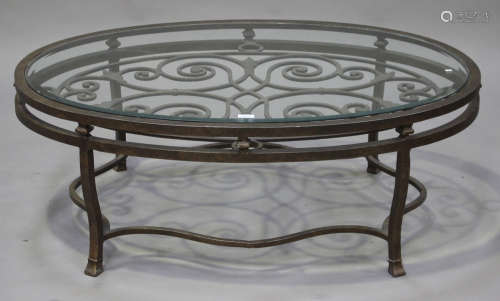 A modern bronzed aluminium and glass oval coffee table with scrolling decoration