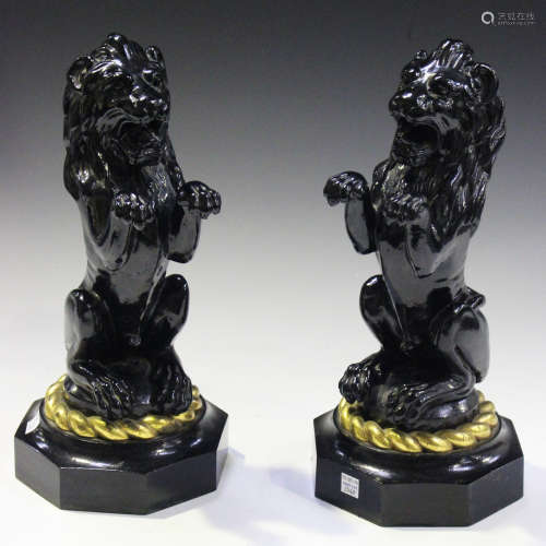 A pair of late 19th/early 20th century black painted cast iron models of lions seated on their hind legs