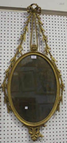 A George III giltwood oval wall mirror with a ribbon and laurel leaf surmount