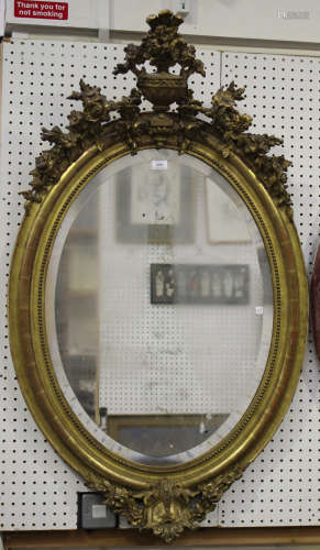A mid-Victorian giltwood and gesso framed oval wall mirror with urn surmount