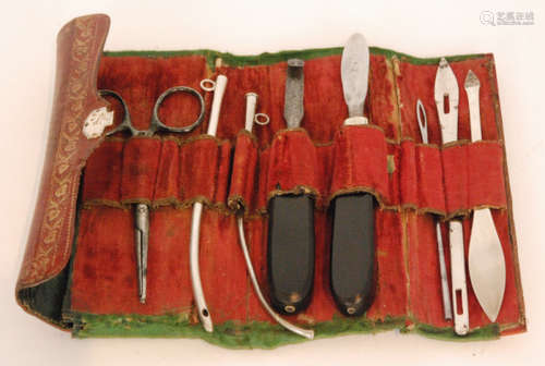 An early 19th Century red leather roll opening to reveal nine assorted implements to include scissors