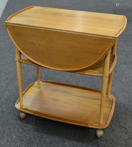 A post war Ercol beech and elm three tier drop leaf serving trolley on swivel castors