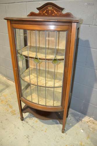 An Edwardian mahogany bow front display cabinet enclosed by a coloured leaded light glazed door