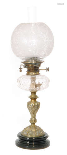 A Victorian brass oil lamp and floral shade with clear glass reservoir on a brass Bacchus mask and acanthus base