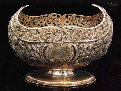 A hallmarked silver oval pedestal sugar basin with embossed foliate decoration below pierced shaped border