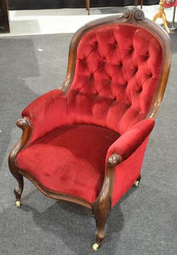 A Victorian carved mahogany framed easy chair with scroll arms upholstered in deep buttoned back crimson plush