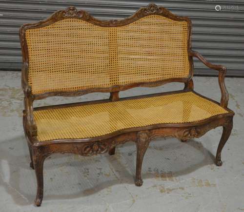 A late 19th to early 20th Century French bergere style two seat settee of serpentine outline