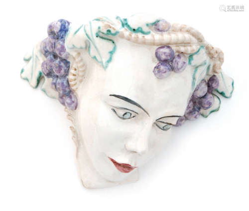 A Continental Art Deco wall pocket modelled after the actress Tilly Losch in downward gaze with fruiting vine head dress picked out in enamel colours over a white tin glazed ground