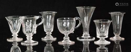 An early 19th Century glass custard cup with ovoid moulded bowl and applied scroll kick handle above a baluster stem and conical foot