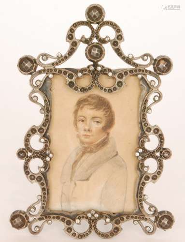 A 19th Century white metal stone set easel photograph frame encompassing a three quarter length watercolour and pencil portrait of a young man