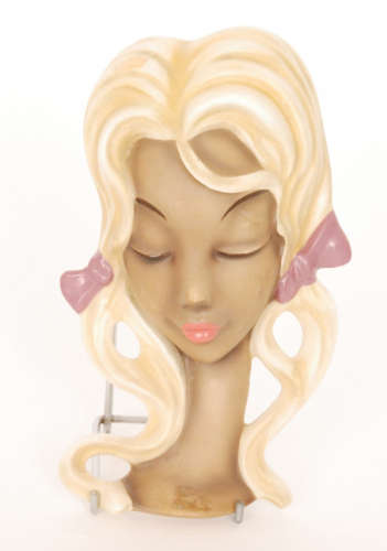 A post war West German face mask modelled as a blonde haired lady with purple ribbons in her hair