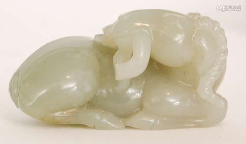 A Chinese pale celadon jade carving of a recumbent goat or ram with its head turned back holding a branch of  lingzhi fungus in its mouth