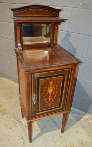 A late Victorian mahogany and part ebonised marquetry inlaid pot cupboard enclosed by an urn and husk swag decorated door