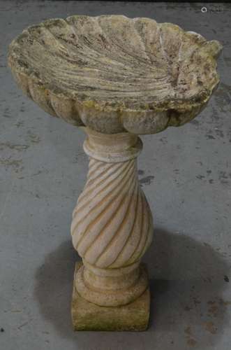 A contemporary garden bird bath of scallop shell form above a wrythen baluster shaped pedestal